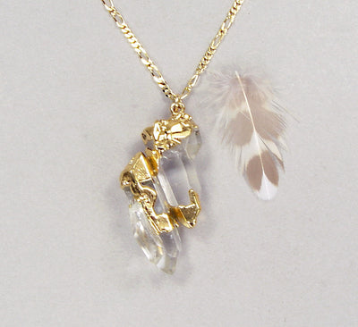 A quartz crystal pendant accented with 18k gold on a gold-filled chain